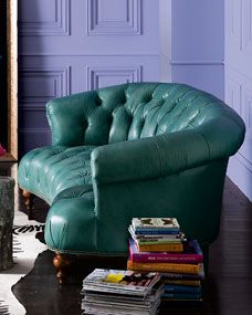 a green leather chair sitting on top of a wooden floor next to a pile of books