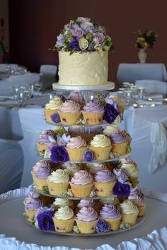 a three tiered cake with cupcakes on it