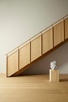 a white sculpture sitting on top of a wooden block next to a stair case and handrail