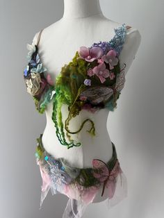 a white mannequin with flowers and butterflies on it's chest, in front of a gray background