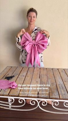 a woman sitting at a table with a pink bow on it