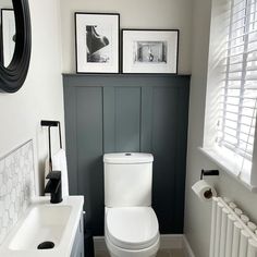 a white toilet sitting in a bathroom next to a sink and radiator with pictures on the wall