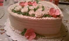 a cake with pink and white flowers on it sitting on a doily covered table