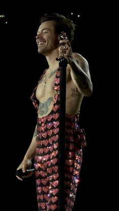 a man with tattoos on his chest holding a microphone in front of a black background