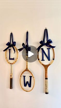 three tennis racquets with the letter n on them hanging from a wall