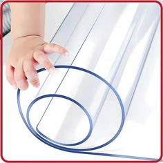 a baby's hand is touching the edge of a clear plastic sheet with blue circles on it