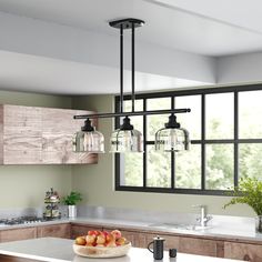 a kitchen with a bowl of fruit on the counter and three lights hanging from the ceiling