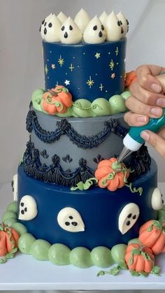 a person is decorating a three tiered cake with halloween decorations on the side