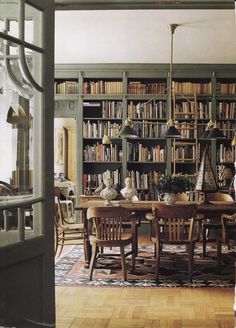 a dining room table and chairs in front of a bookshelf full of books