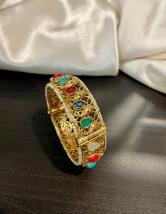 Traditional Temple Navrathan / Navratan / Multicolor Semi Precious stone studded openable Ganesh Motif Bracelet Bangle in Matte gold finish. A perfect piece of art always a keeper in your jewelry trinket that goes with Ethnic Attire /  Indian outfits.  👉🏻Size Available:  2.5 Openable  ✅Check other styles available in our store https://www.etsy.com/shop/KKsCulture Send us an email if you need help!  SHIPPING & TURNAROUND  👉🏻Please check listings for shipping and turnaround times.  👉🏻We foll Multicolor Bracelet With Intricate Design As A Gift, Multicolor Bracelets With Intricate Design For Gift, Multicolor Bracelets With Intricate Design As Gift, Stone Work Bracelets For Puja And Festivals, Traditional Bracelets With Stone Work For Gifts, Traditional Stone Work Bracelet For Gift, Festive Stone Work Bracelets For Puja, Multicolor Bracelet Jewelry For Puja, Traditional Stone Work Bracelets For Festive Occasions