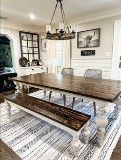 a large wooden table sitting in the middle of a living room next to a rug