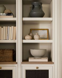 a white bookcase filled with books and vases