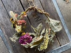 a wreath made out of dried flowers sitting on top of a wooden fence