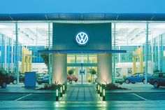 the front entrance to a volkswagen dealership at night with cars parked in the parking lot