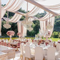 an outdoor dining area with tables, chairs and chandeliers set up for a formal function