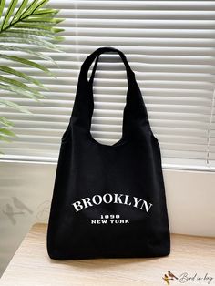 the brooklyn new york bag is sitting on a table next to a potted plant