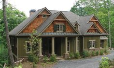 a house in the woods with lots of trees and flowers on the front lawns