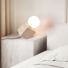 a lamp sitting on top of a bed next to a white pillow in a room