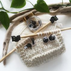 a knitted hat with black cats on it and two knitting needles next to it