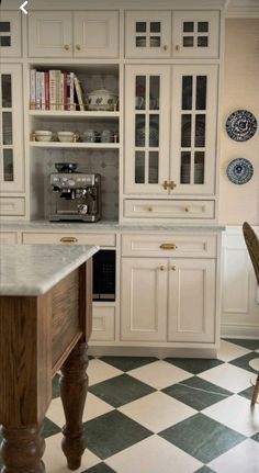 a kitchen with white cabinets and black and white checkered flooring on the floor