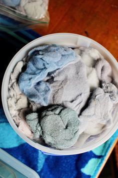 a white bowl filled with blue and grey colored powder on top of a wooden table