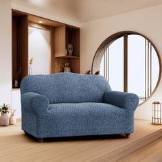 a blue couch sitting on top of a hard wood floor next to a round window