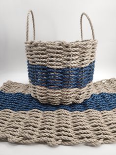 two baskets sitting on top of each other with rope handles and blue trimmings