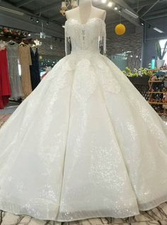 a white ball gown on display in a store with lots of dresses hanging from the ceiling