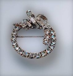 "Sparkling clear rhinestone circle wreath brooch. Graduated round stones, topped with a swirl of bezel set baguettes. I'm not sure if this is white gold or rhodium plated. 1 1/2\" x 1 1/4\" Marked 'CINER©' Other than a touch of wear to the pin, everything is in very good condition. Stones are sparkly and all are present. Thank you for shopping at The Looking Glass Plus!" Vintage Diamond Round Brooches, Elegant Round Brooches With Rhinestones, Elegant Round Rhinestone Brooches, Elegant Round Brooches For Vintage Events, Anniversary Rhinestone Round Brooches, Anniversary Brooches With Rhinestones, Anniversary Round Rhinestones Brooches, Anniversary Round Brooches With Rhinestones, Silver Crystal Round Brooches