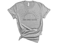 HERE COMES THE SUN TEE. This soft and comfortable tee can easily be layered under a denim or flannel shirt. Spread a little sunshine anytime of the year! ABOUT THE TEE This unisex shirt is soft and lightweight, with the right amount of stretch. It's a comfortable and flattering for both men and women. * 100% combed and ring-spun cotton (Heather colors contain polyester) * Ash color is 99% combed and ring-spun cotton, 1% polyester * Heather colors are 52% combed and ring-spun cotton, 48% polyeste Unisex Band Merch T-shirt For Summer, Summer Unisex Text Print Shirt, Unisex Text Print Shirt For Summer, Summer Text Print Shirt, Summer Tri-blend Crew Neck Shirt, Hippie T Shirts, Boho Tees, Hippie Shirt, Retro 60s