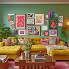 a living room filled with yellow couches and colorful paintings on the wall above them