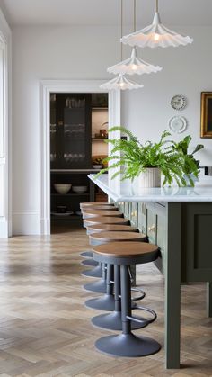 a kitchen with several stools and plants on the counter top in front of it