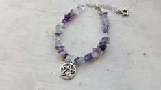 Pentacle Bracelet made with silver toned metal charms and semi precious stones. Pick a crystal. Adjustable chain with a star charm on the end of it. I take custom orders. Amethyst Clear Quartz Black jasper Green Aventurine Rainbow Fluorite Rose Quartz Note: due to the nature of natural chip stones, each piece will be unique. Note: this item is made to order and may take a week to 2 to ship. If you would like a color/crystal not shown, message me and I most likely can get it. Adjustable Silver Crystal Bracelet, Silver Adjustable Crystal Bracelet, Silver Spiritual Crystal Bracelet, Spiritual Silver Crystal Bracelet, Silver Charm Bracelet With Natural Stones For Healing, Adjustable Star-shaped Magical Jewelry, Adjustable Mystical Silver Bracelet, Adjustable Silver Mystical Bracelet, Spiritual Silver Crystal Bracelet With Rose Quartz