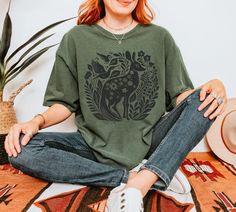 This shirt effortlessly blends the whimsical charm of nature with a touch of rustic elegance, making it a perfect addition to any wardrobe that appreciates the finer details of life. Whether you're strolling through a sun-dappled forest or enjoying a quiet afternoon in a blooming garden, this t-shirt will envelop you in a sense of floral bliss. The soft-washed, garment-dyed fabric brings extra coziness to your wardrobe while the relaxed fit makes it an excellent daily choice. The double-needle s Cottagecore Relaxed Fit Graphic Print Shirt, Cottagecore Printed T-shirt With Relaxed Fit, Cottagecore Summer T-shirt With Plant Print, Cottagecore T-shirt With Plant Print For Spring, Spring Cottagecore T-shirt With Plant Print, Deer Shirt, Floral Tee, Granola Girl, Floral Vintage