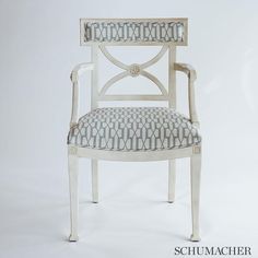 a white chair with a blue and white patterned upholstered seat on the back