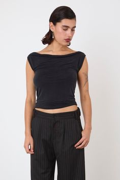 a woman wearing black pants and a cropped top is looking down at her stomach