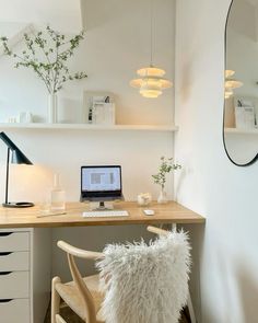 a laptop computer sitting on top of a wooden desk next to a white chair and lamp