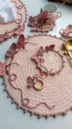 pink crocheted placemats and napkins on a table with gold utensils