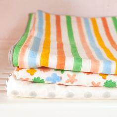 three folded towels are stacked on top of each other in different colors and patterns,