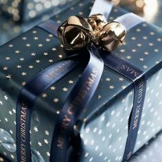 a christmas present wrapped in blue and gold with a bow on it's side