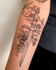 a woman's arm with flowers and a knife on it