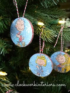 three ornaments hanging from a christmas tree with peanuts on them, one is blue and the other is yellow