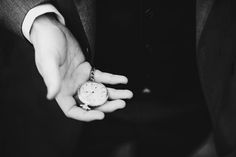 a person wearing a suit and holding an old pocket watch in their hand with both hands