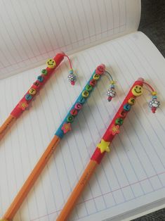 two pencils with smiley faces on them are sitting in an open notepad next to each other