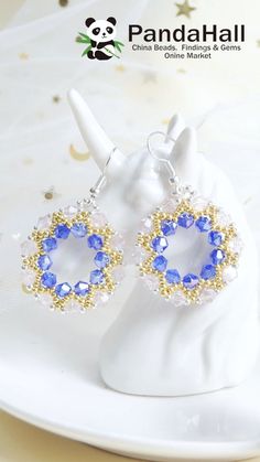 a pair of blue and white earrings sitting on top of a white plate