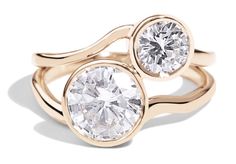 two gold rings with white stones on each one and an oval diamond in the middle