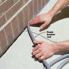 a man is working on the side of a brick wall with a hose attached to it