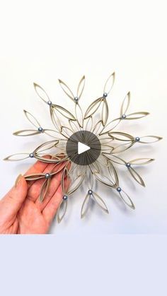 a hand holding a metal object with leaves on it's center and an arrow in the middle