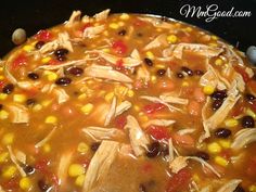 a pot full of soup with corn and carrots on the side, ready to be cooked