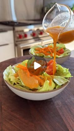 a person pouring dressing into a salad in a bowl with lettuce and carrots